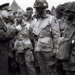 General Eisenhower talking to paratroopers, emphasizing the importance of full victory before they embark on their mission to Europe.