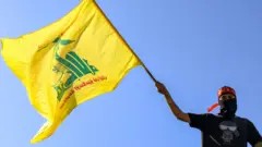 AFP A masked demonstrator waves a flag of the Lebanese Shiite movement Hezbollah during a demonstration