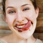 Close-up of a woman demonstrating tongue flexibility, often mistakenly associated with the myth of the tongue being the strongest muscle in the human body.