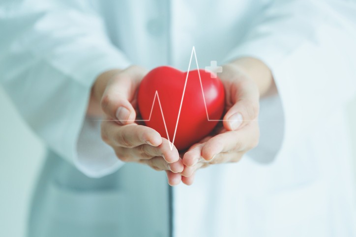 Female medical doctor holding red heart shape in hand with graphic of heart beat, cardiology and insurance concept