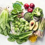 Colorful and diverse foods rich in vitamin K, including leafy greens, cheese, and berries, arranged on a white background to highlight their nutritional value.