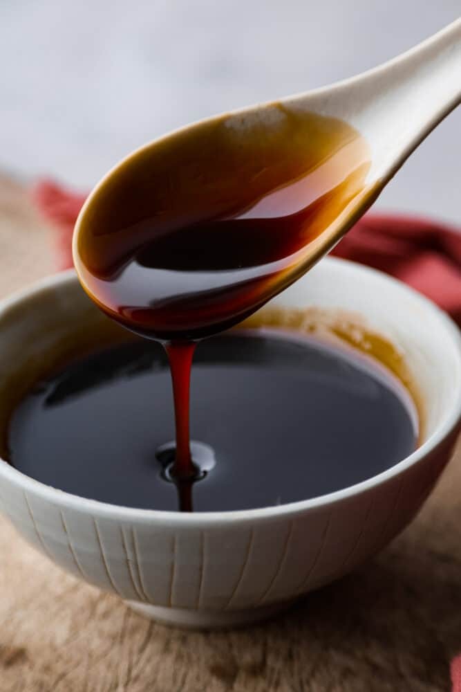 Close-up of eel sauce being drizzled from a spoon, highlighting its thick and glossy texture.