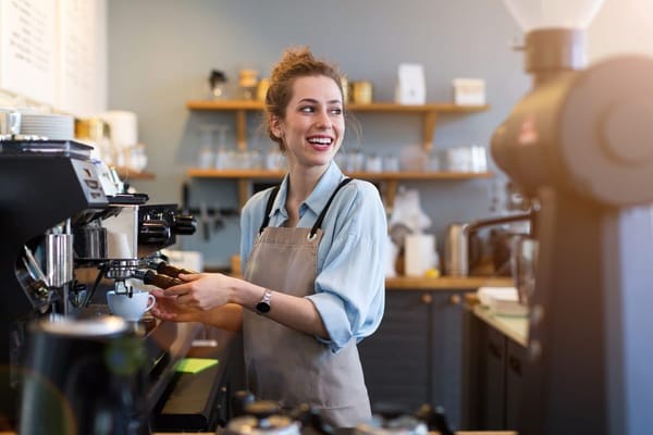 Smiling barista preparing an espresso shot, a crucial step in making a delicious Americano.