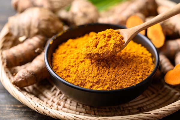 Close-up of turmeric powder and fresh turmeric root, highlighting curcumin's vibrant color and natural source