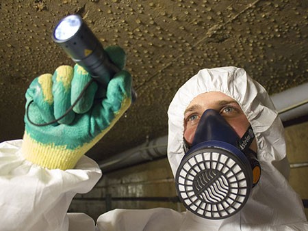 Professional asbestos surveyor wearing safety mask, emphasizing expertise in asbestos identification