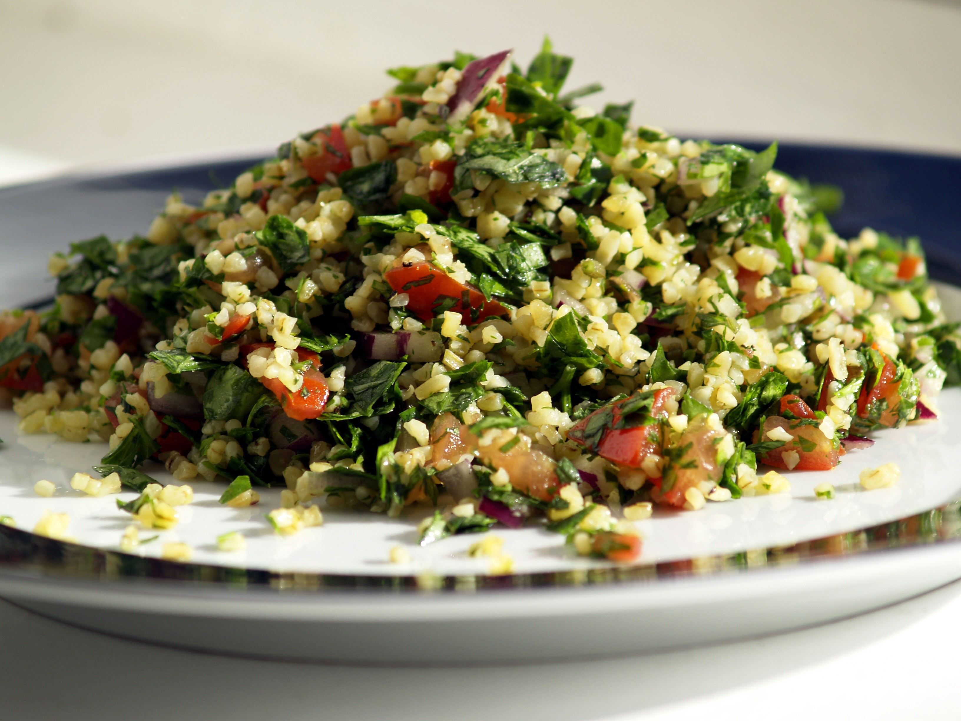 A vibrant and fresh plate of traditional Levantine Tabbouleh salad, highlighting the finely chopped parsley, mint, and tomatoes mixed with bulgur and lemon dressing.