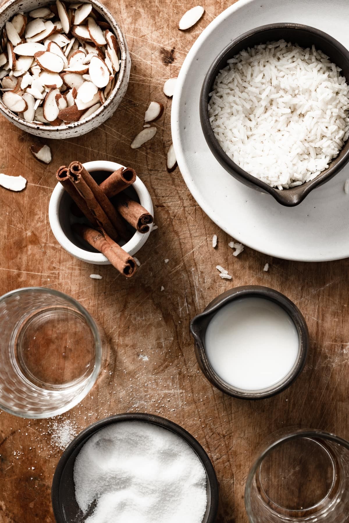 Horchata ingredients shown here including rice, almonds, cinnamon, stick, water, milk, and sugar.