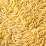 Close-up of uncooked orzo pasta revealing its rice-like shape.