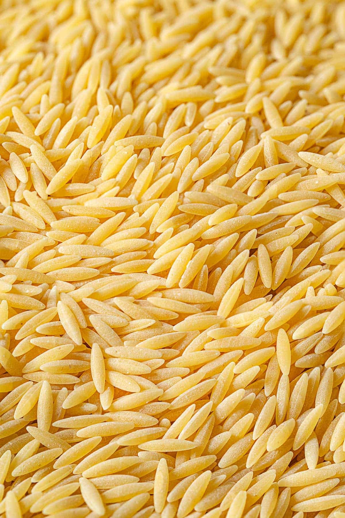 Close-up of uncooked orzo pasta revealing its rice-like shape.