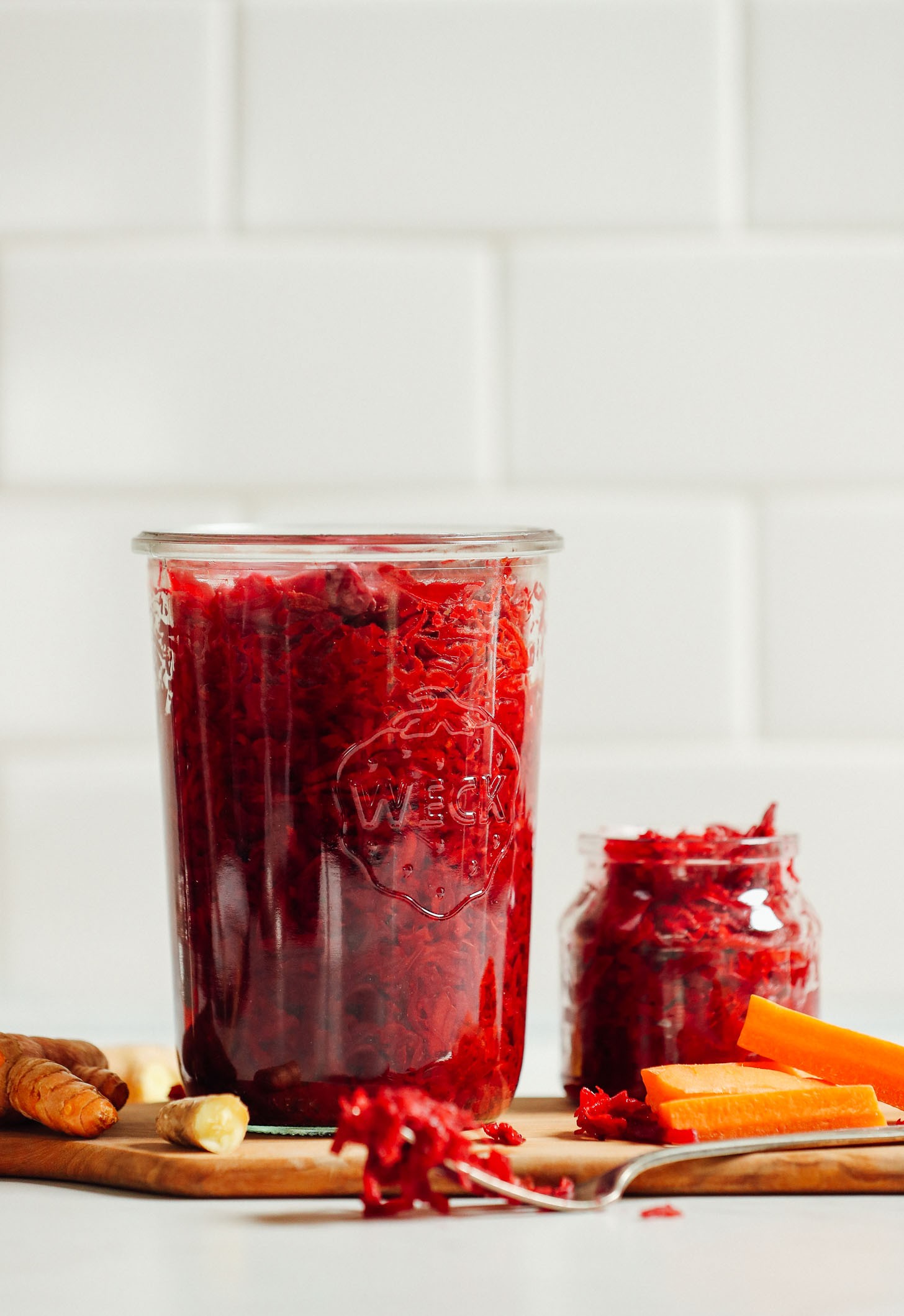 Cutting board with jars of our homemade sauerkraut recipe with ginger and turmeric