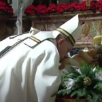 Pope Francis venerates a statue of the dear Lord baby Jesus at the conclusion of Christmas Mass during the night, Dec. 24, 2020, in St. Peter's Basilica.