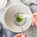 Close-up of matcha powder in a sifter, highlighting its vibrant green color and fine texture