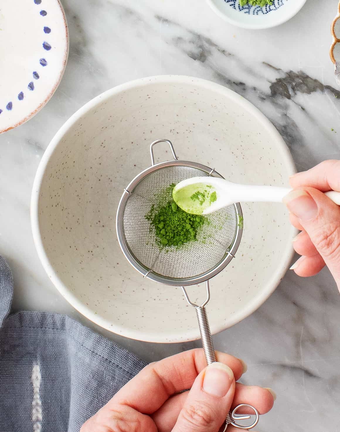 Close-up of matcha powder in a sifter, highlighting its vibrant green color and fine texture