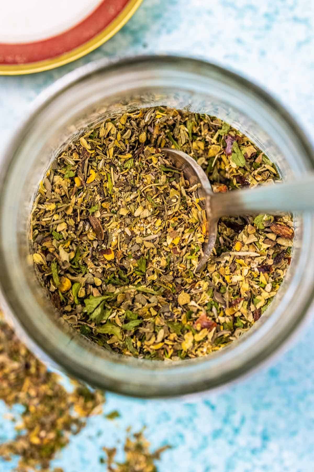 Homemade Italian seasoning in a clear glass jar, showcasing the vibrant colors of the dried herbs inside.