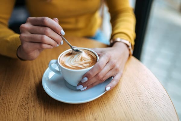 Barista stirring a latte, illustrating the steamed milk component that distinguishes it from an Americano.