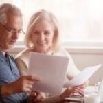 An older couple reviews Medicare enrollment information on a laptop, highlighting the importance of understanding what sign is march for health coverage decisions