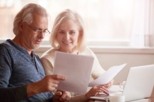 An older couple reviews Medicare enrollment information on a laptop, highlighting the importance of understanding what sign is march for health coverage decisions