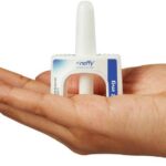 A hand holding a Neffy nasal spray device showcasing its white nozzle, blue label, and rectangular design, emphasizing its intended use for medical applications.