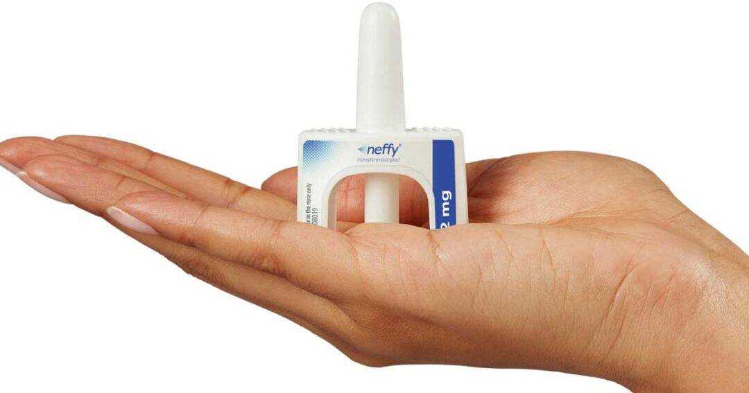 A hand holding a Neffy nasal spray device showcasing its white nozzle, blue label, and rectangular design, emphasizing its intended use for medical applications.