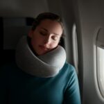 Woman sleeping on a plane using Go Neck Pillow by Ostrichpillow