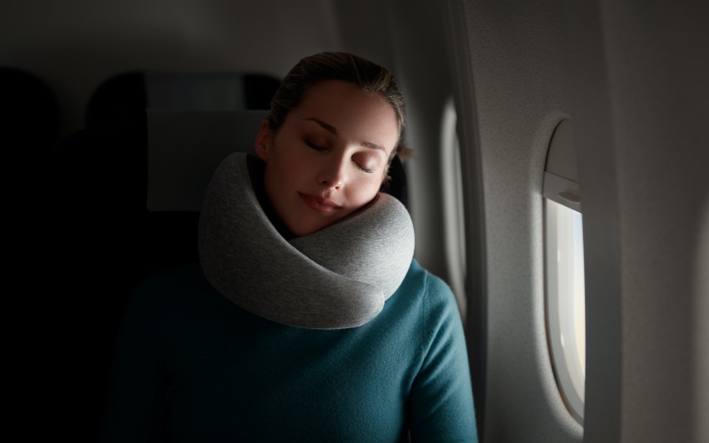 Woman sleeping on a plane using Go Neck Pillow by Ostrichpillow