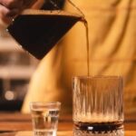 Close-up of an Americano being poured, showing the crema on top of this simple espresso and water coffee drink.