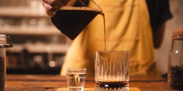 Close-up of an Americano being poured, showing the crema on top of this simple espresso and water coffee drink.