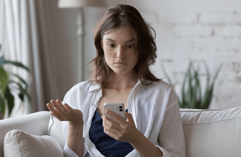 Confused woman looking at her phone, wondering about text abbreviations like YW