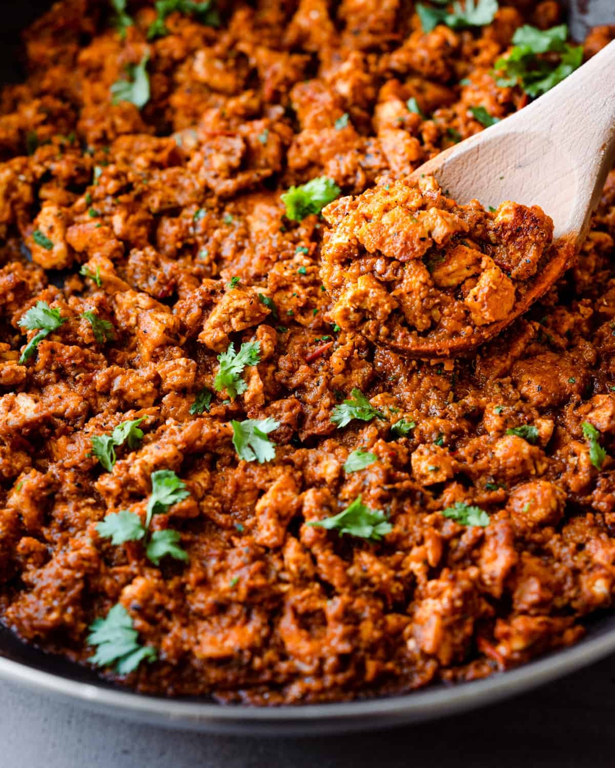 Close up of sofritas and wooden spoon in a frying pan.