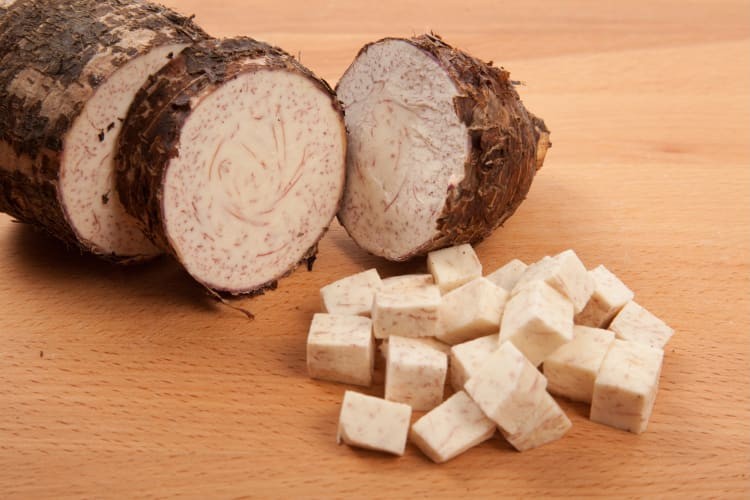 Close-up of sliced taro root showcasing its rough brown skin and pale interior with purple speckles