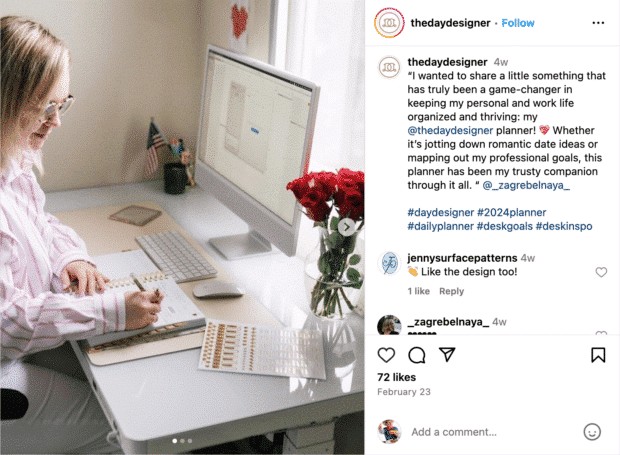 A Day Designer planner open on a desk, showcasing its layout, with a person's hand writing in it.