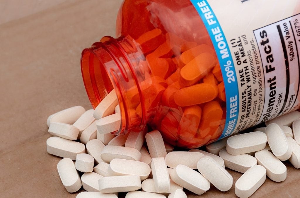 Orange bottle lying on its side with white multivitamins spilling out