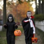 Two boys (6-7) wearing Halloween costume on sidewalk, portrait