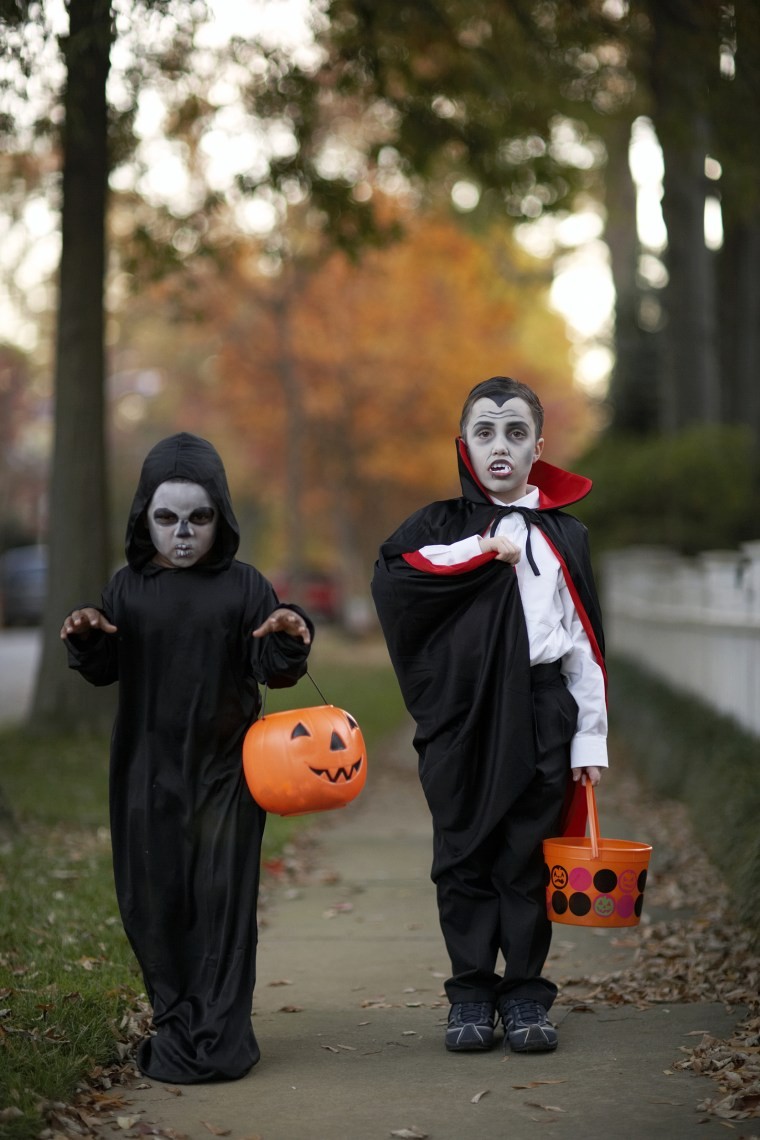 Two boys (6-7) wearing Halloween costume on sidewalk, portrait