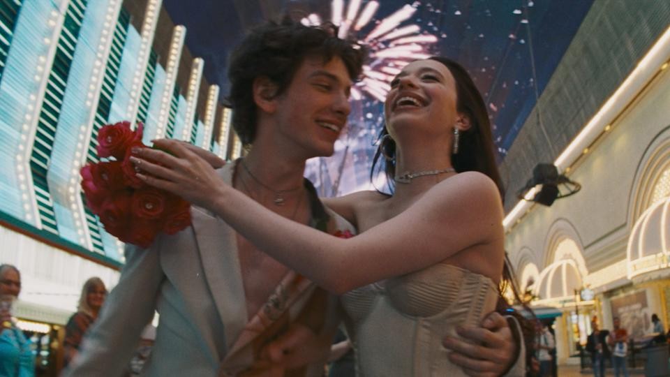 Mikey Madison and Mark Eydelshteyn as Anora and Ivan walking on the Vegas Strip at night, embracing