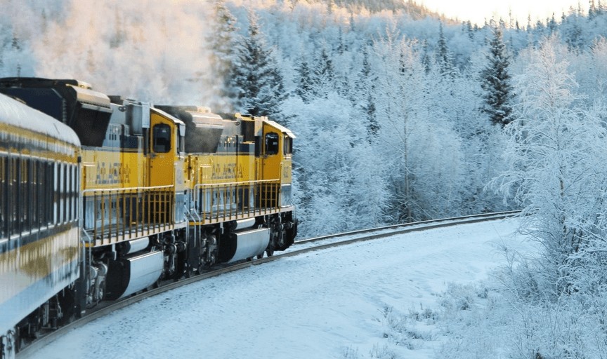 A train in Alaska surrounded by snow-covered trees.