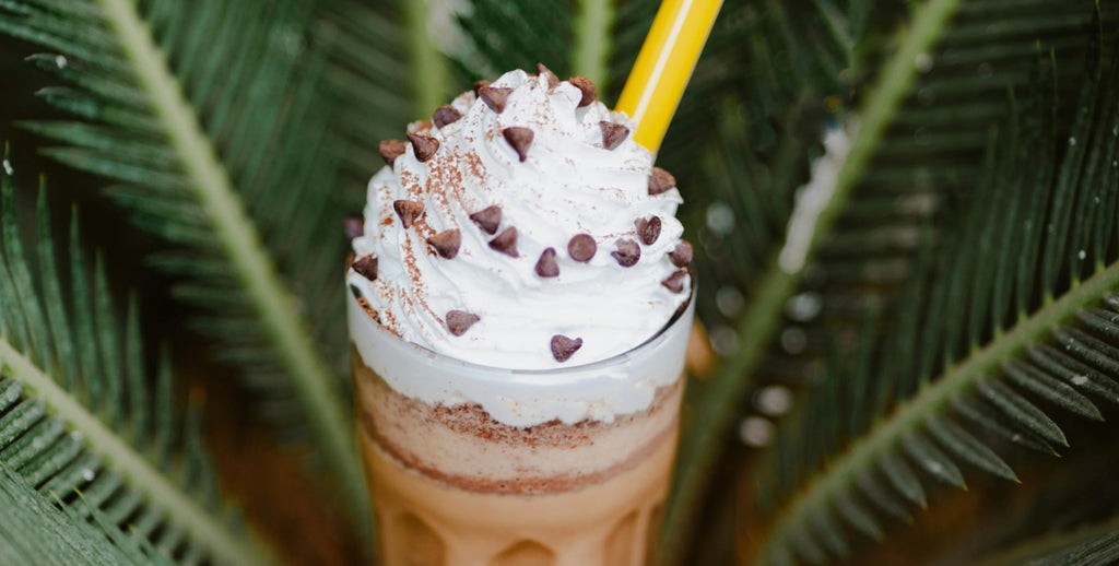 Starbucks Frappuccino with whipped cream and caramel drizzle, logo visible on cup, cafe interior setting