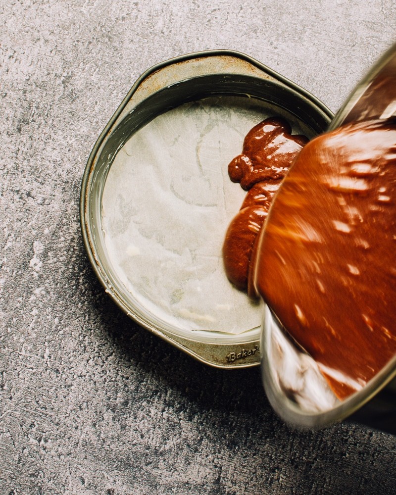 Chocolate Cake Batter being poured into parchment paper-lined baking pan.