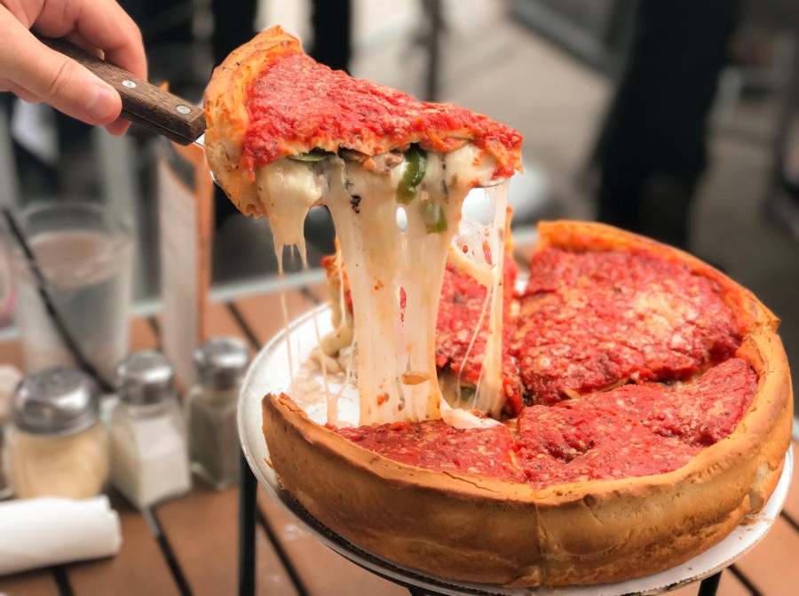 A slice of Chicago-style deep dish pizza with cheese and tomato sauce