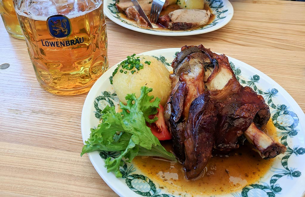 People raising their beer steins inside a crowded Oktoberfest tent
