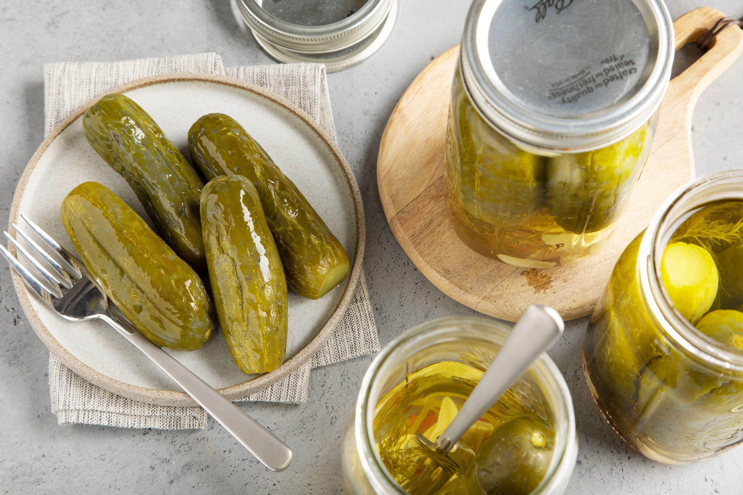 Assortment of homemade pickles on a plate beside jars of pickles