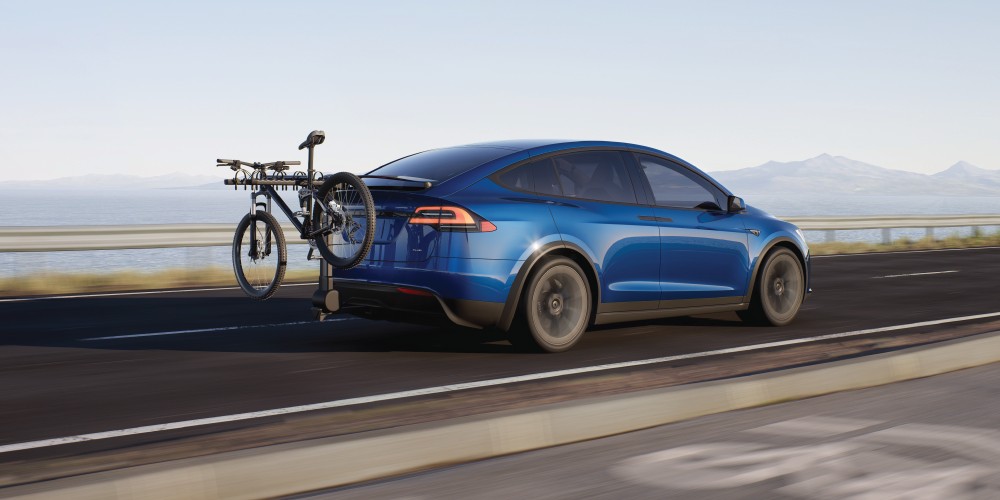 A silver Tesla Model X driving along a highway