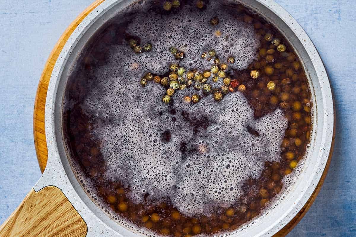 Green lentils cooking in a saucepan, showing the simmering process