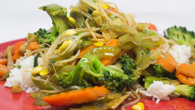 A close-up of a steaming bowl of chop suey, showcasing the diverse ingredients such as meat, bean sprouts, and colorful vegetables, all coated in a rich, glossy sauce.